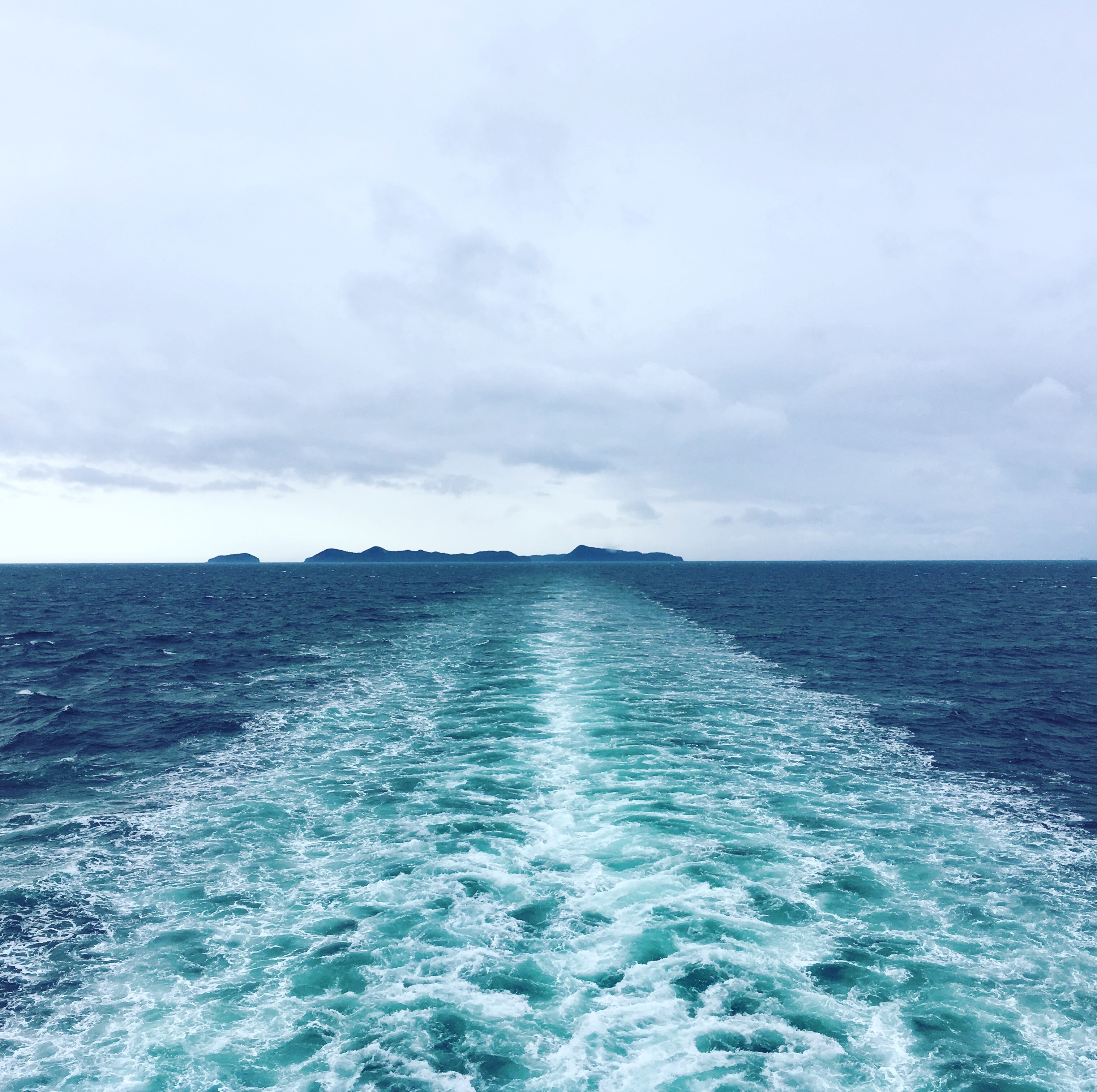 Turquoise ocean wake stretching toward distant islands